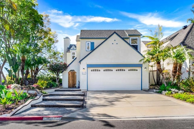 view of front of property featuring an attached garage, a chimney, driveway, and stucco siding