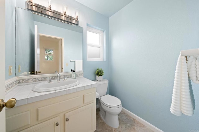 half bath with baseboards, toilet, and vanity