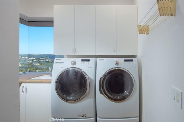 washroom featuring washing machine and dryer, cabinet space, and a sink