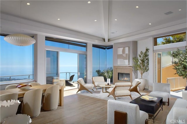 living room featuring recessed lighting, wood finished floors, a glass covered fireplace, and a water view