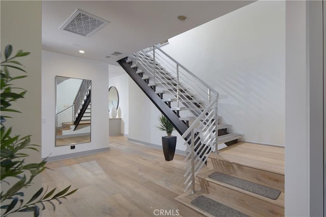 staircase featuring recessed lighting, visible vents, baseboards, and wood finished floors