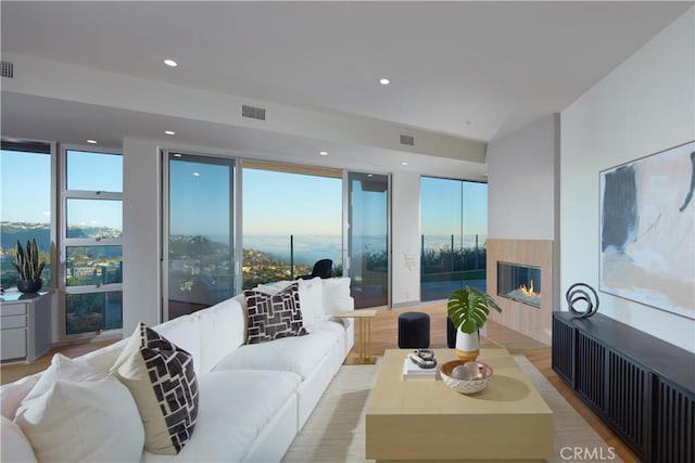 living area featuring a multi sided fireplace, visible vents, floor to ceiling windows, and recessed lighting