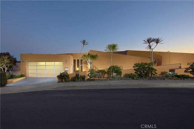 view of front facade featuring stucco siding, concrete driveway, and an attached garage