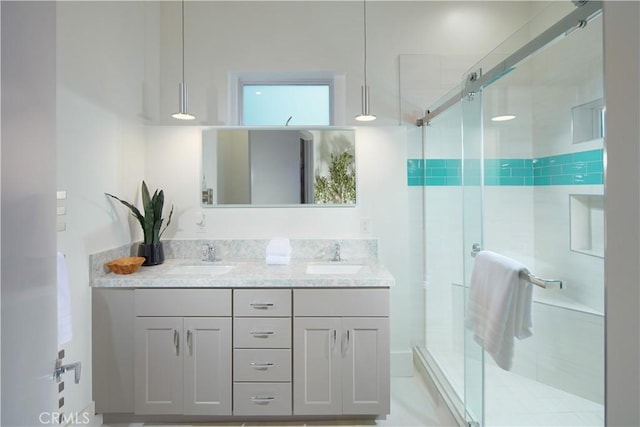 full bath featuring double vanity, a stall shower, and a sink