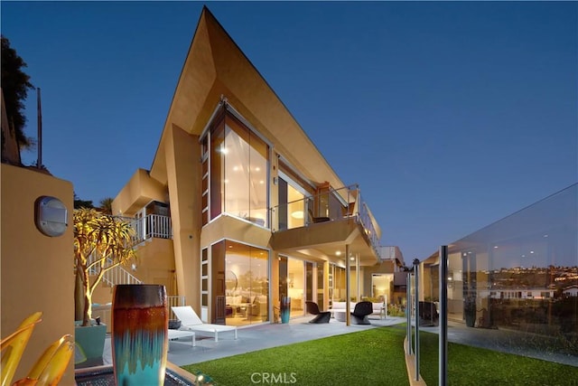 back of house featuring a lawn, a patio, and a balcony