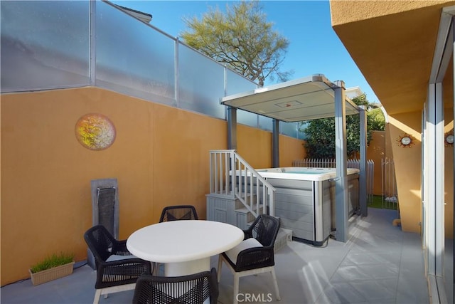 view of patio featuring outdoor dining space, a hot tub, and fence