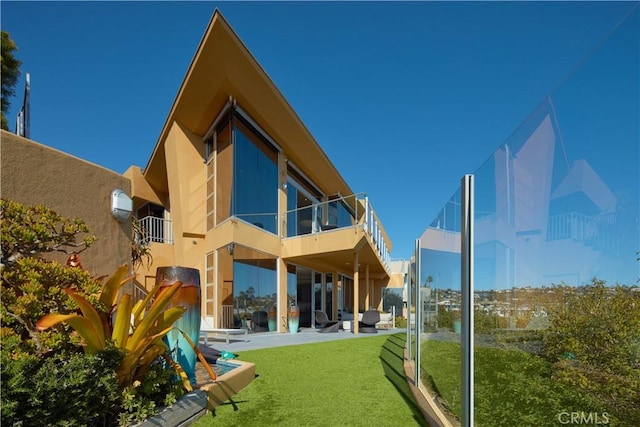 back of house with a yard, a patio, a balcony, and stucco siding