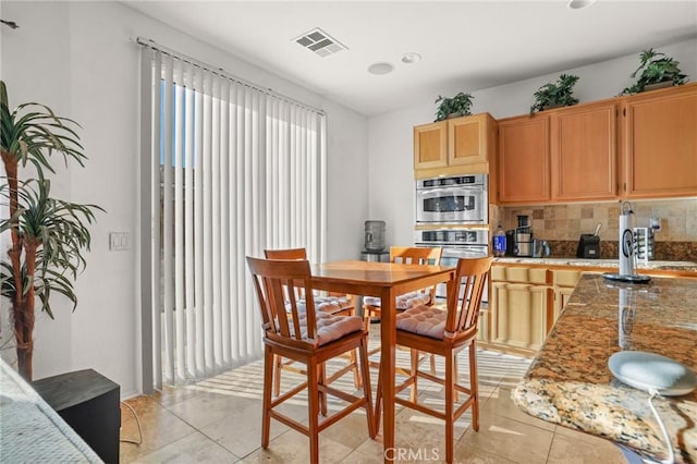 dining space with light tile patterned floors and visible vents