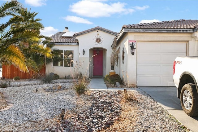 mediterranean / spanish-style home with solar panels, an attached garage, driveway, and stucco siding