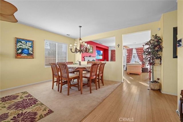 dining area featuring visible vents, baseboards, an inviting chandelier, and wood-type flooring