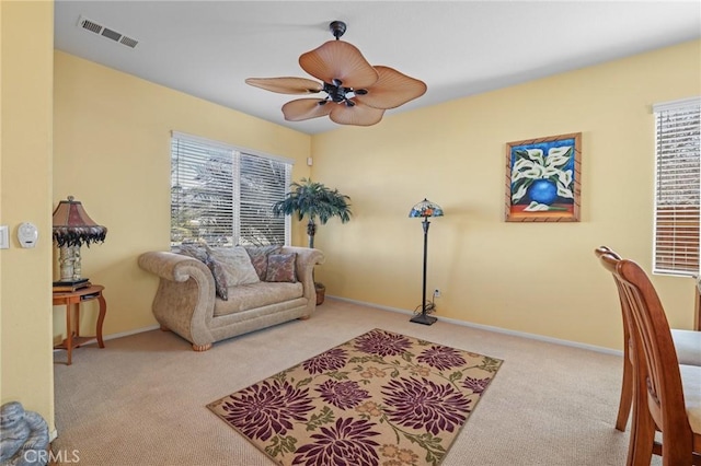 interior space with carpet flooring, a ceiling fan, visible vents, and baseboards