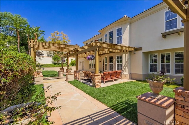 back of property with a patio area, a pergola, a yard, and stucco siding