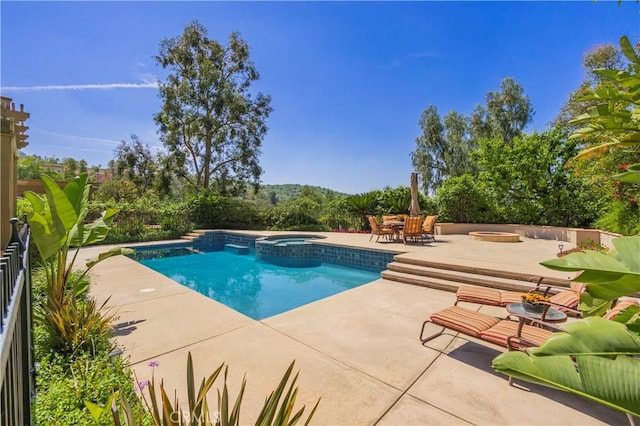 view of pool featuring a patio, a pool with connected hot tub, and a fire pit