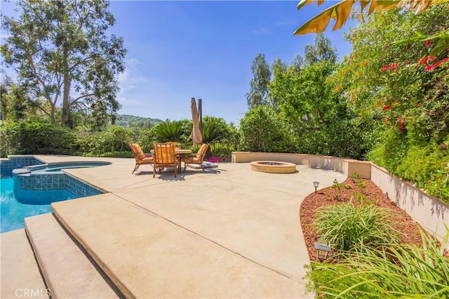 view of patio / terrace featuring an outdoor fire pit, an in ground hot tub, and a fenced in pool