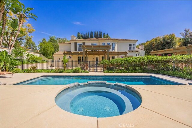 view of swimming pool with a pool with connected hot tub, fence, and a patio