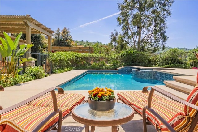 view of swimming pool featuring a pool with connected hot tub, fence, and a patio area