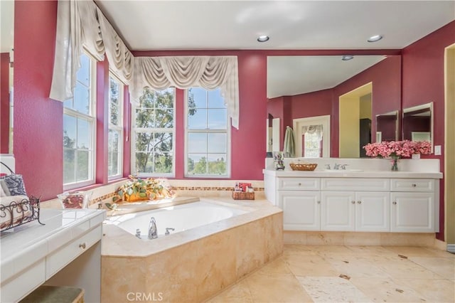 bathroom featuring a garden tub, vanity, and a healthy amount of sunlight
