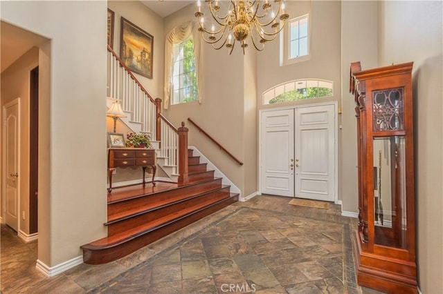 entrance foyer featuring a chandelier, stairs, a high ceiling, and baseboards