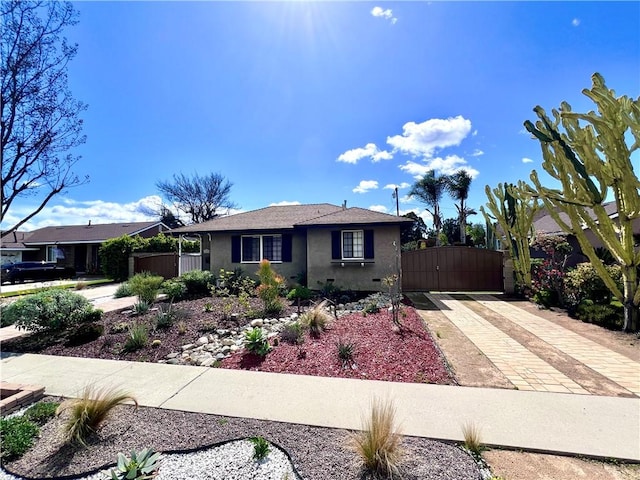 view of front of house with stucco siding, driveway, and a gate