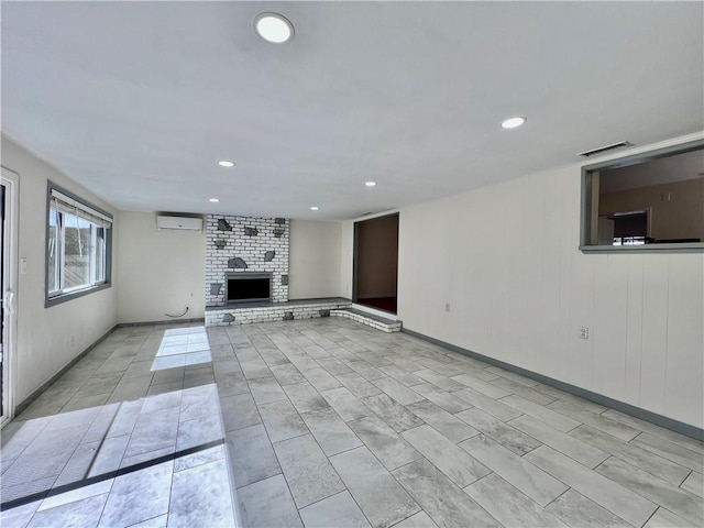 unfurnished living room with a wall unit AC, visible vents, baseboards, recessed lighting, and a fireplace