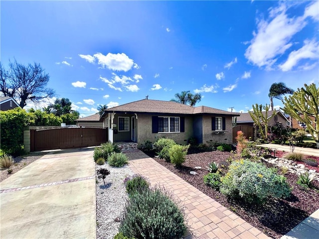 ranch-style home with stucco siding, fence, driveway, and a gate