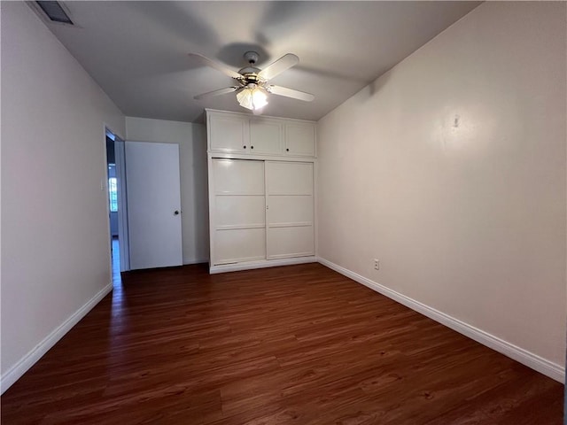 unfurnished bedroom with visible vents, ceiling fan, baseboards, and dark wood-style flooring