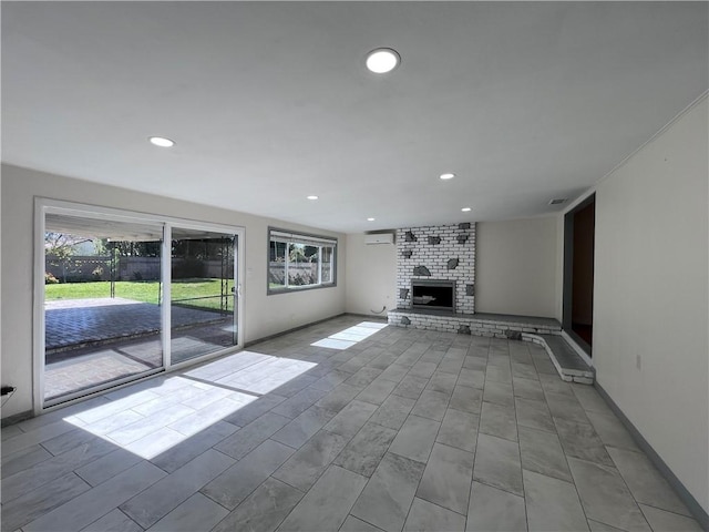 unfurnished living room featuring recessed lighting, baseboards, and a brick fireplace