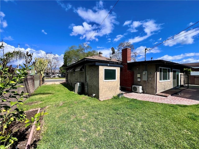 back of property featuring stucco siding, a lawn, a patio, fence, and a chimney