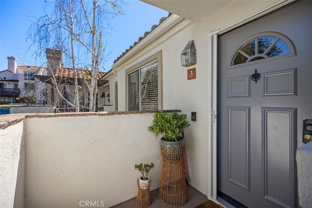 property entrance with a residential view, stucco siding, and a balcony