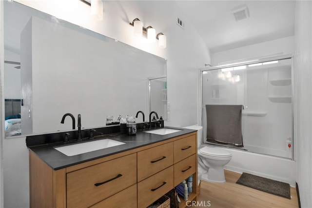 bathroom featuring a sink, toilet, wood finished floors, and double vanity