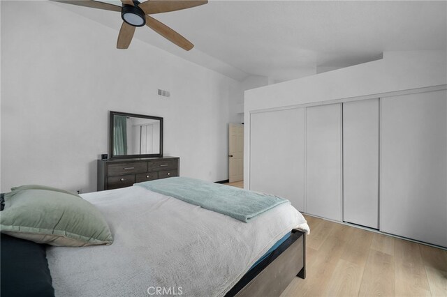 bedroom with visible vents, a ceiling fan, wood finished floors, a closet, and vaulted ceiling