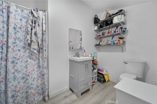 bathroom featuring vanity, toilet, wood finished floors, and baseboards