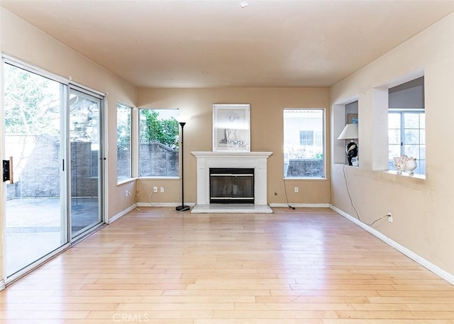 unfurnished living room featuring a glass covered fireplace, light wood-style floors, and baseboards