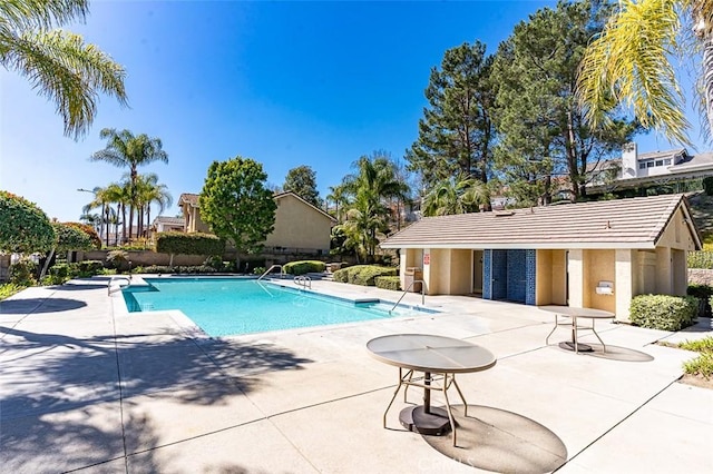 community pool with an outdoor structure and a patio area