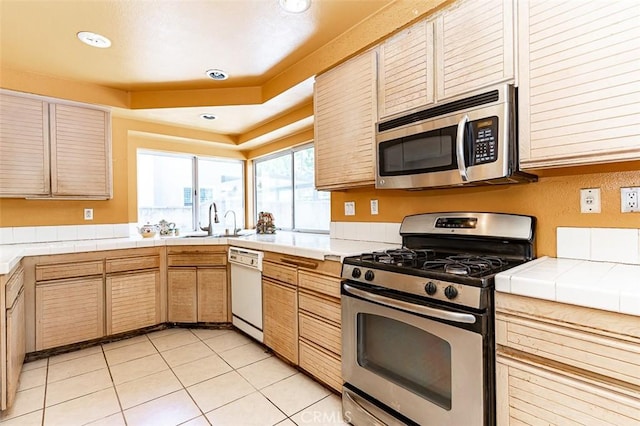 kitchen featuring tile counters, light tile patterned floors, recessed lighting, appliances with stainless steel finishes, and a sink