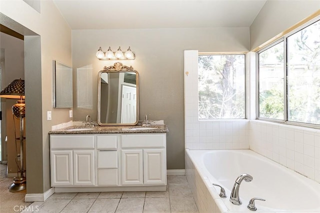 bathroom featuring baseboards, a garden tub, double vanity, tile patterned floors, and a sink