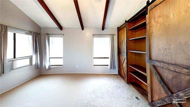 interior space with a barn door, carpet, and vaulted ceiling with beams