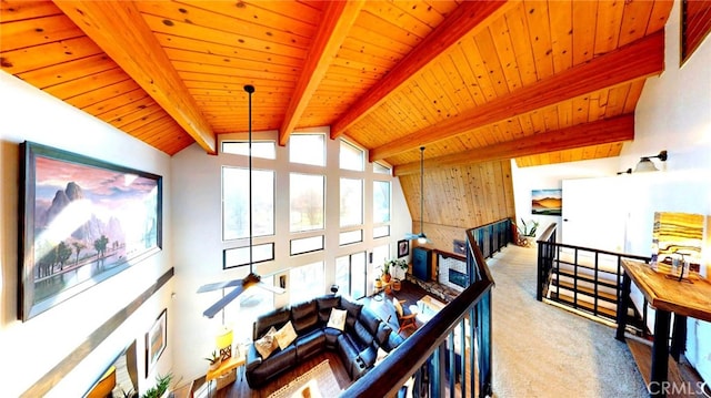 carpeted living area with wooden ceiling, vaulted ceiling with beams, and a ceiling fan