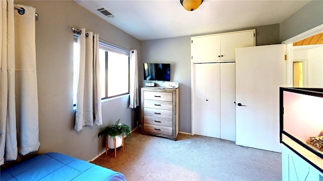 bedroom featuring visible vents, light carpet, and a closet