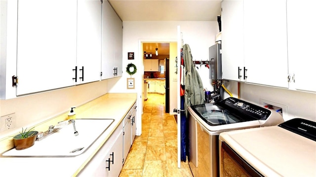 kitchen featuring a sink, white cabinetry, light countertops, and washing machine and clothes dryer