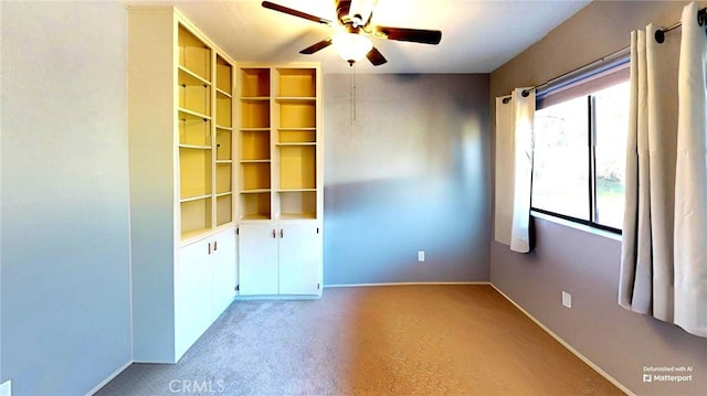 unfurnished room featuring a ceiling fan, light colored carpet, and baseboards