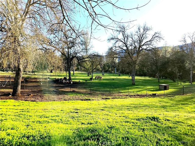 view of community featuring a rural view, a lawn, and fence