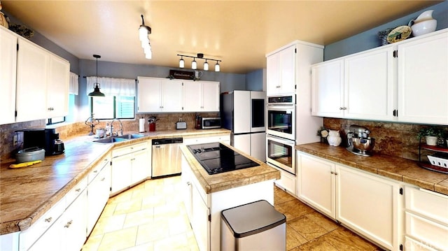 kitchen featuring a kitchen island, a sink, stainless steel appliances, white cabinetry, and tasteful backsplash