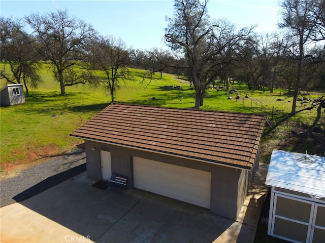 view of community featuring a yard, a detached garage, and an outbuilding