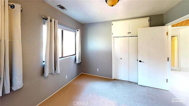 unfurnished bedroom with visible vents, a closet, and carpet flooring