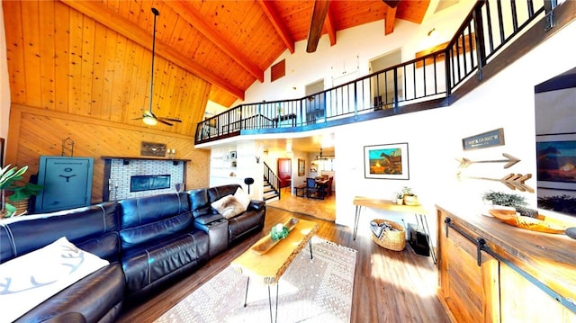 living room with beamed ceiling, stairway, wood ceiling, wood finished floors, and a glass covered fireplace