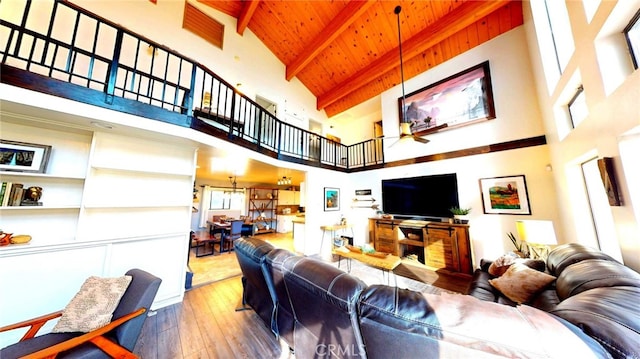 living area with hardwood / wood-style floors, a ceiling fan, beam ceiling, wood ceiling, and a towering ceiling