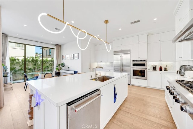 kitchen featuring visible vents, a center island with sink, a sink, under cabinet range hood, and stainless steel appliances