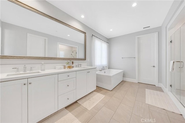 full bath featuring a sink, a freestanding bath, a stall shower, and double vanity