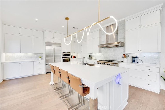 kitchen featuring light countertops, appliances with stainless steel finishes, light wood-style floors, white cabinetry, and a sink